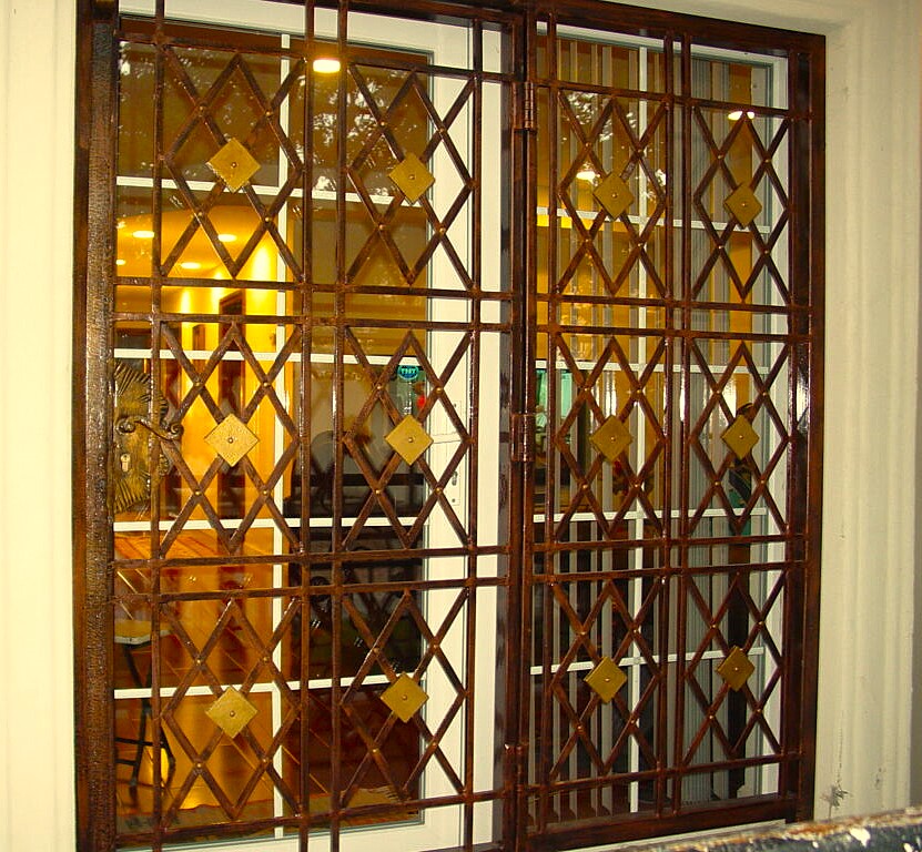 Copper-brown lattice grille on glazed doors with brass diamonds and warm light inside