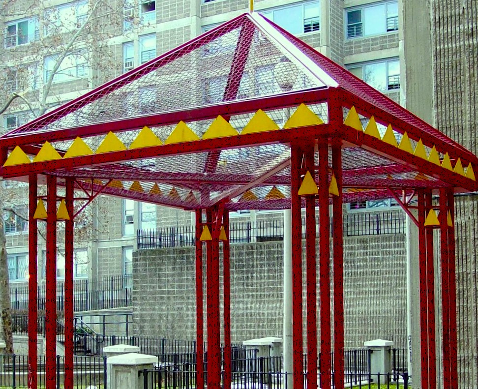 Red painted gazebo with yellow trim and mesh roof outside a tall apartment block