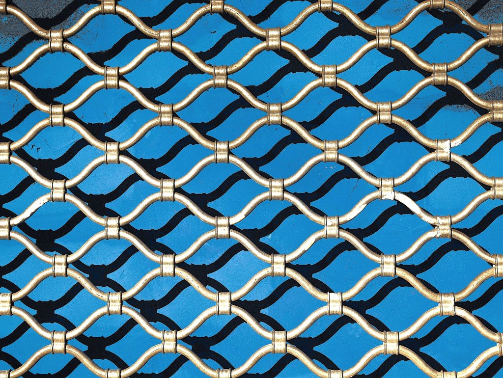 Gold-finished diamond lattice grille against a vivid blue painted panel