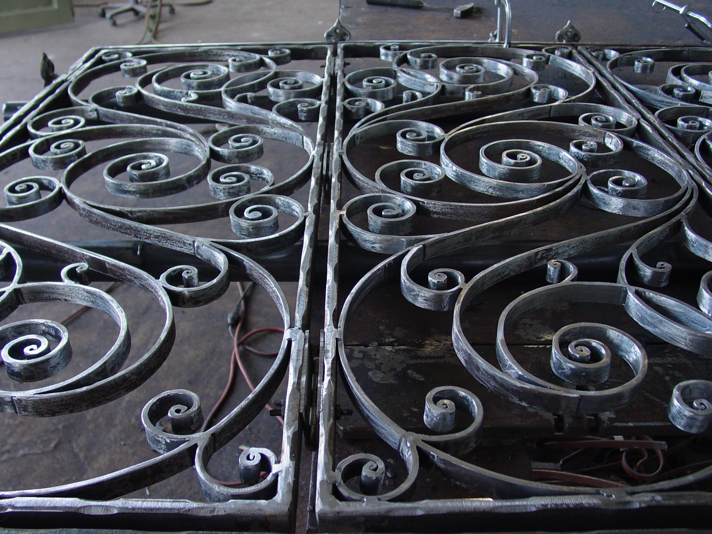 Hand-forged scrollwork panels laid out in the workshop
