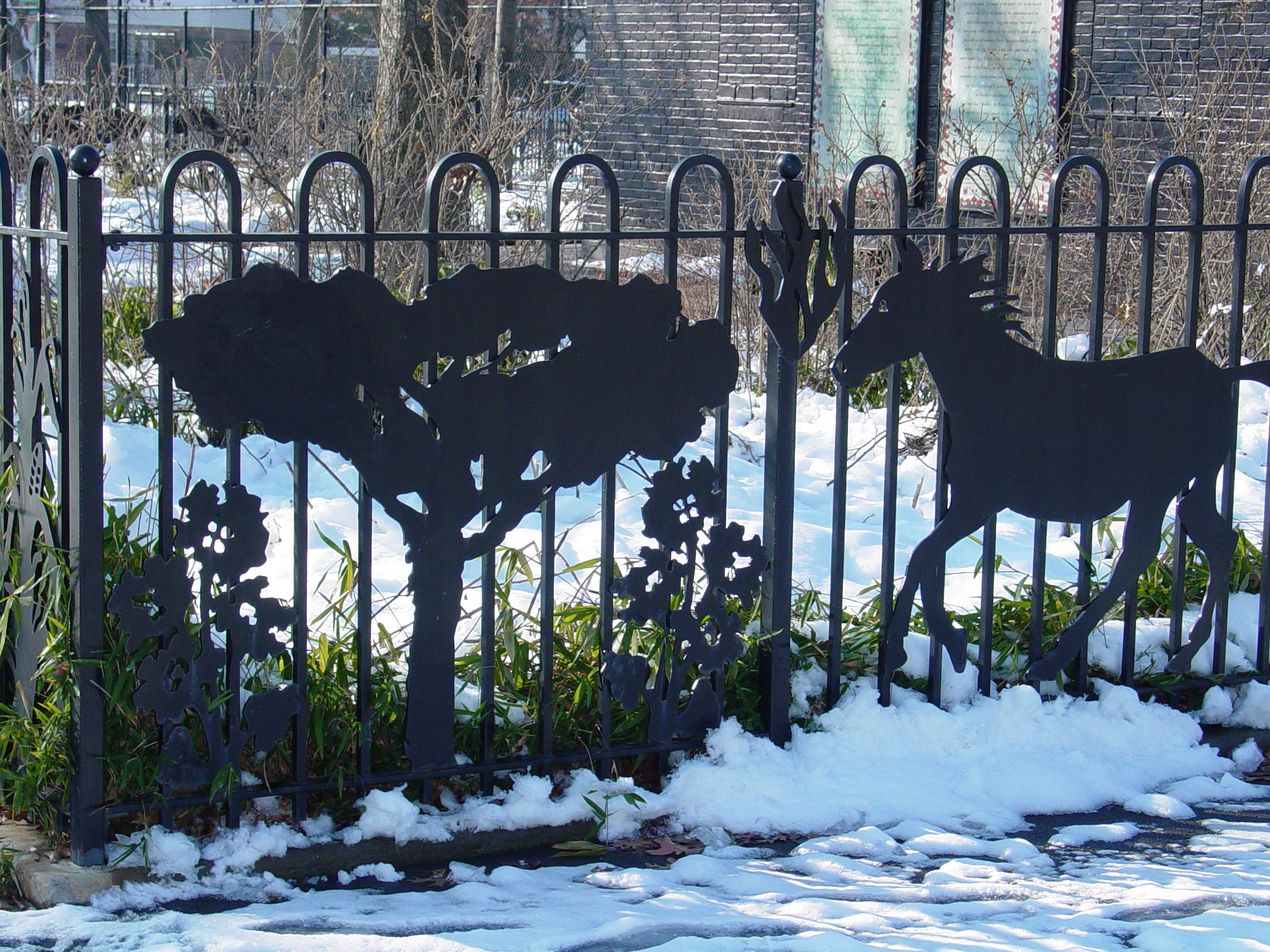 Ornamental park fence with silhouetted trees and wildlife