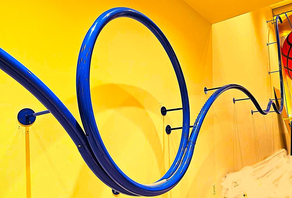Painted tube bent into a full circle, bracketed to a yellow wall